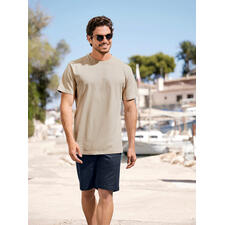 Sand Lachender Mann im beigen T-Shirt und blauen Shorts bei einem Spaziergang am Hafen.