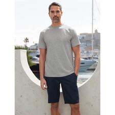Grau-meliert Mann in grauem T-Shirt und blauen Shorts am Hafen.