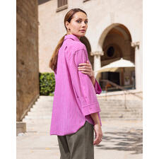 Streifenbluse 2.0 Frau in pink gestreifter Bluse mit Blick über die Schulter vor historischem Gebäude.