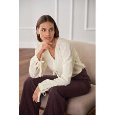 Baumwoll-Kaschmir-Crinkle-Bluse Frau sitzt in einer hellen Baumwoll-Kaschmir-Bluse mit gebundenen Ärmeln.