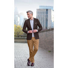 Bordeaux Mann im braunen Sakko steht in Stadtumgebung.