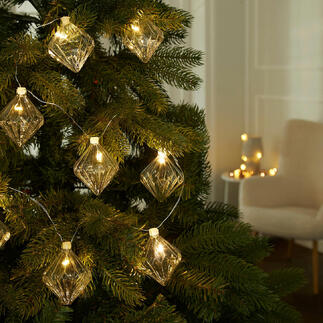 Lichterkette mit gläsernen Ornamenten am Weihnachtsbaum.