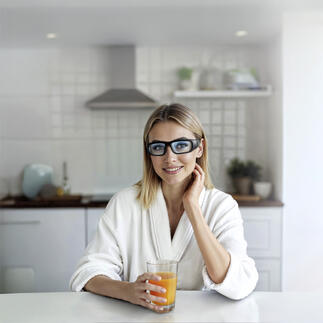 Frau mit Lichtbrille in der Küche bei der Einnahme eines Getränks.