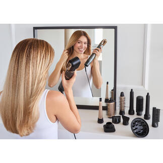 Frau stylt ihr Haar mit einem 12-in-1 Hair-Styler vor einem Spiegel.