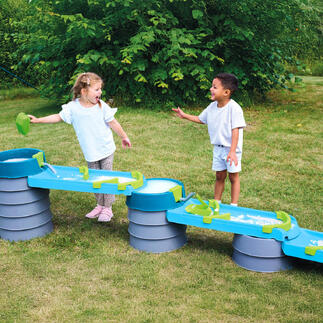 Zwei Kinder lachen und spielen an der Wasser- und Matschbahn.