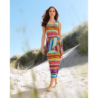 Frau in buntem Regenbogen-Kleid auf Sanddünen.