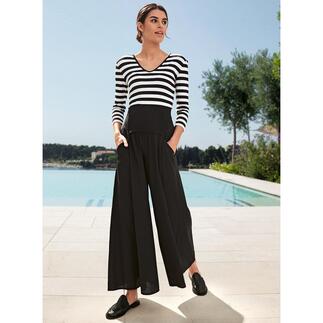 Frau in gestreiftem Zauber-Shirt mit schwarzer Hose, steht vor Schwimmbad.