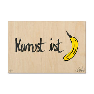 Holzplatte mit der Aufschrift 'Kunst ist' und einer gezeichneten Banane.
