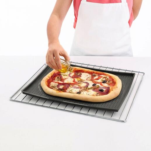 Person ölt eine Pizza auf einer knusprigen Backmatte