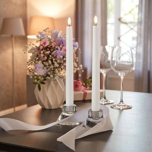 Zwei LED-Stabkerzen in einer dekorativen Umgebung neben Blumen.