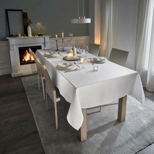 Weißer Tisch mit festlicher Tischdecke in Leinenoptik und Kerzen.