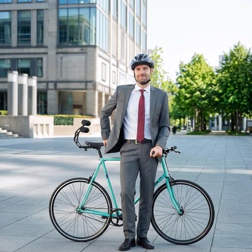 Mann in Anzug steht mit Fahrrad und Tshobo Fahrrad-Rückenstütze im Freien.