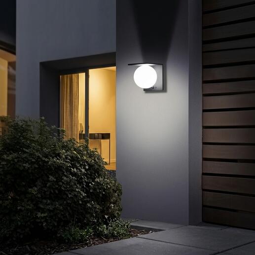 Solar-Kugelwandleuchte an einer Hauswand leuchtet sanft.