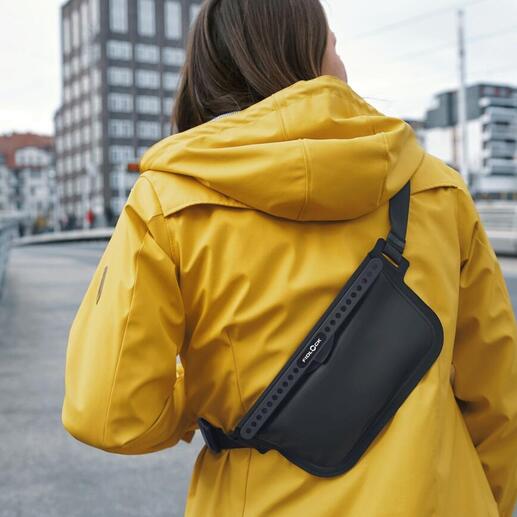 Frau mit gelber Jacke trägt eine schwarze Crossbody-Tasche auf der Schulter.