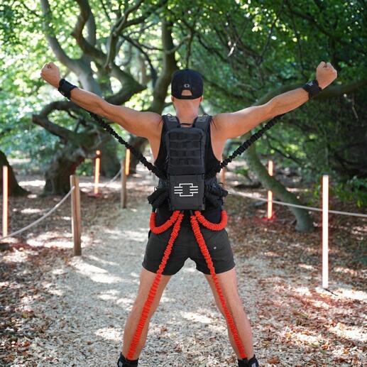 Mann mit Widerstands-Trainingsset, der seine Arme im Freien hebt.
