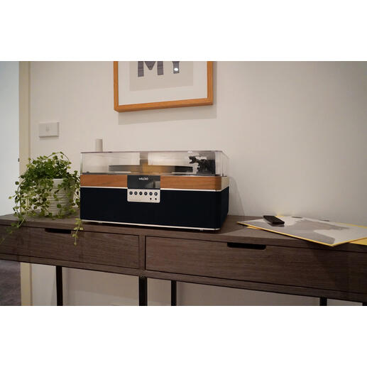 All-in-One-Audiosystem Das revolutionäre All-in-One-Audiosystem für Vinyl-Liebhaber und (Wieder-)Einsteiger. All-In-One-Plattenspieler aus Walnuss auf einem Tisch in einem modernen Raum