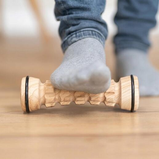Fußmassage-Roller aus Holz, ein Fuß liegt darauf.