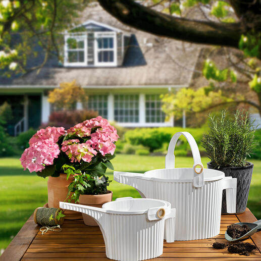 Zwei Gießkanne in Weiß und Blumen auf einem Tisch im Garten