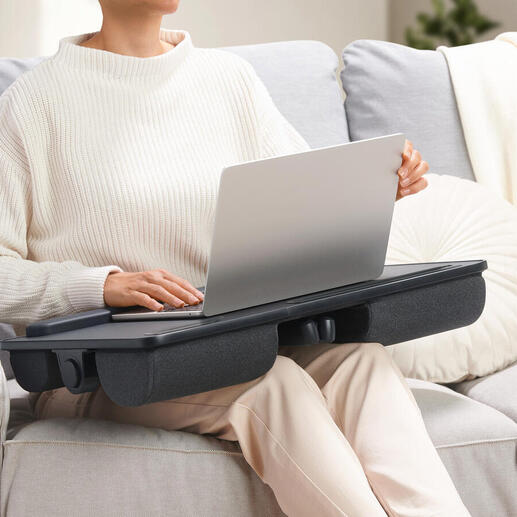 Person mit einem 2-in-1 Laptopkissen auf dem Schoß, das als Tisch dient.