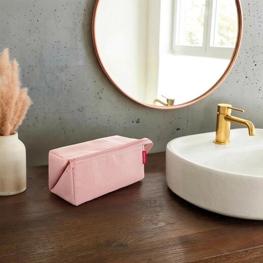Rosa 2-in-1 Reisenecessaire auf einem Holztisch neben einem Waschbecken