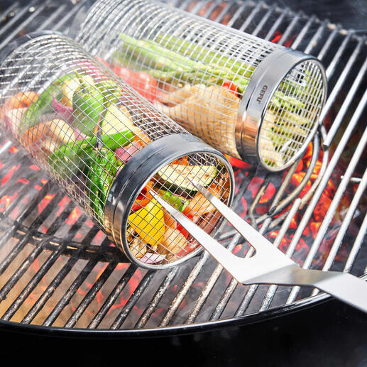 Grillkorb aus Metall mit Gemüse darin, auf dem Grill mit glühenden Kohlen.