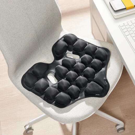 Schwarzes ergonomisches Sitzkissen auf einem Stuhl.