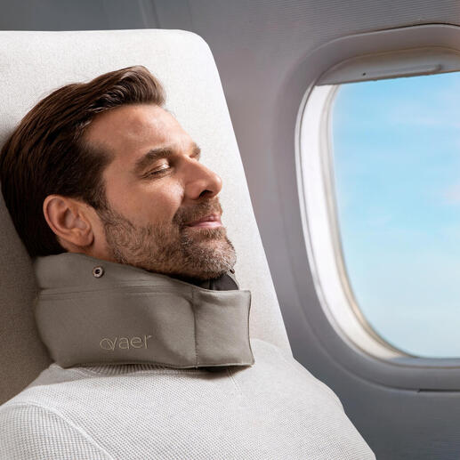 Mann mit Reisekissen entspannt am Fenster im Flugzeug.