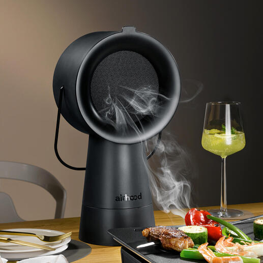 Airhood 2.0 in Schwarz, dampfendes Grillgerät auf Tisch mit Gemüse und Fleisch.
