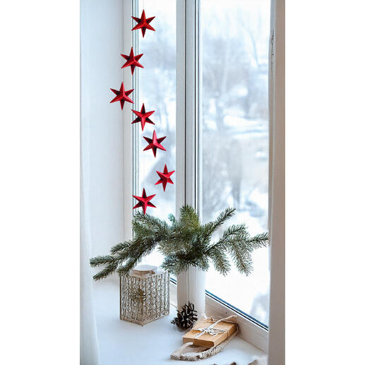 Rotes Mobiles Sternendekor über einer Fensterbank mit Schnee draußen.