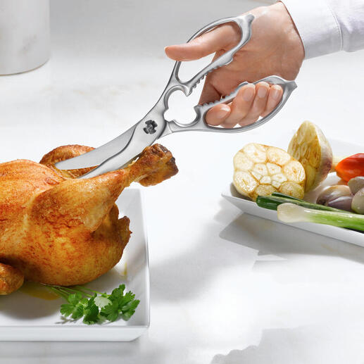 Zwei-in-eins Küchen- und Geflügelschere schneidet ein Hähnchen auf einem Teller.