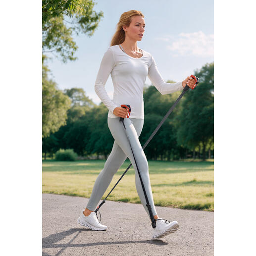 Frau beim power-walking mit Sportgeräten in einem Park.