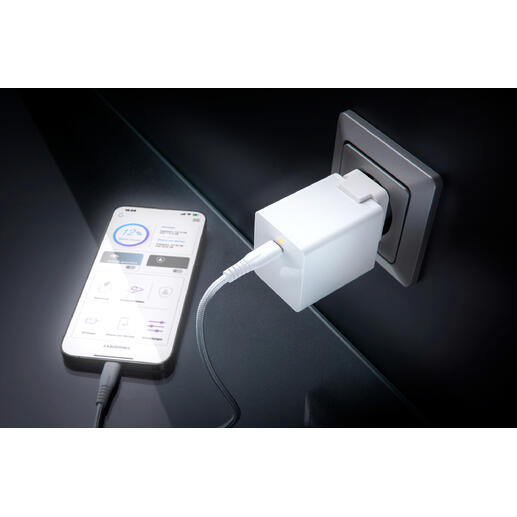 Weißer USB-Ladeadapter steckbar in eine Wandsteckdose, Smartphone angeschlossen.