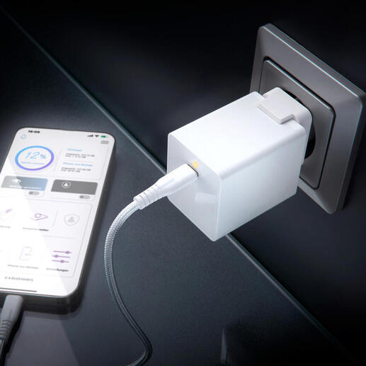 Weißer USB-Ladeadapter steckbar in eine Wandsteckdose, Smartphone angeschlossen.