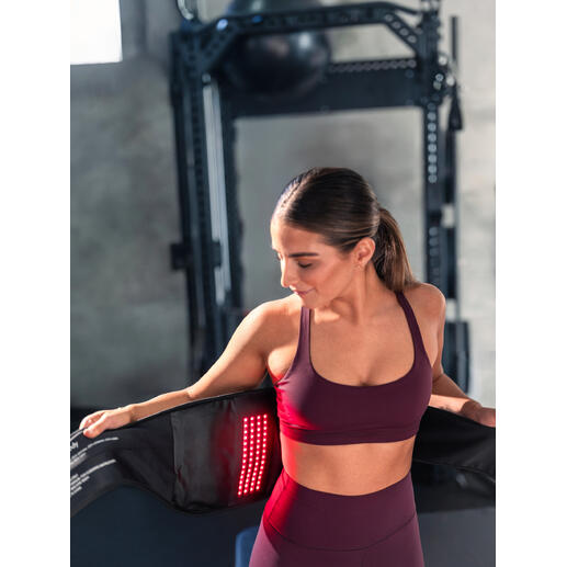 Frau mit 4-in-1 Rückenbandage, in einem Fitnessstudio.