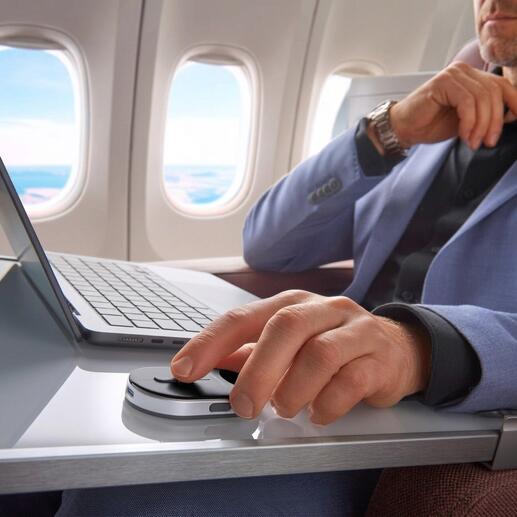 Mann in einem Flugzeug nutzt eine mobile Mini-Maus auf einem Tisch.