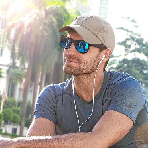 Mann mit beige Kühlkappe und Sonnenbrille sitzt im Freien