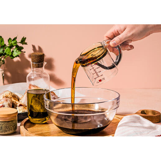Person gießt Öl aus einem Messbecher in eine Schüssel.