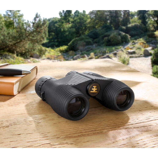 Kompakt-Fernglas auf einem Holztisch in der Natur.