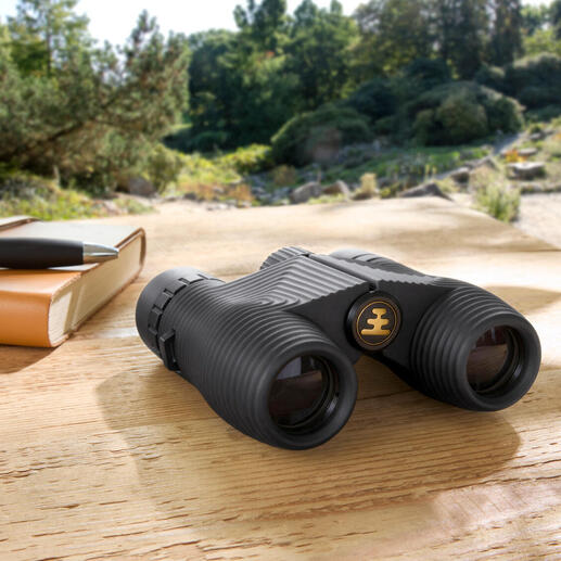 Kompakt-Fernglas auf einem Holztisch in der Natur.