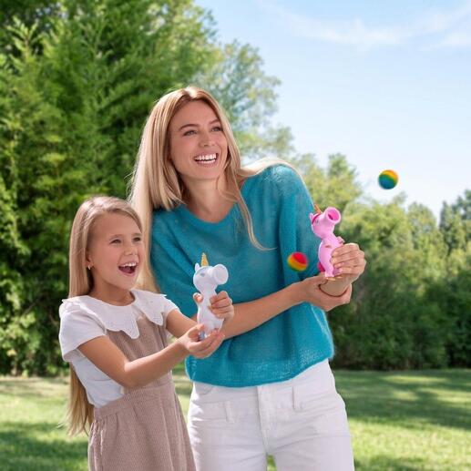 Frau und Mädchen lachen beim Spielen mit Einhorn-Ploppern im Freien.