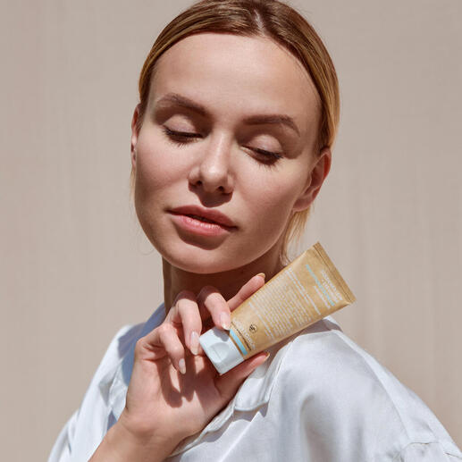 Frau mit geschlossenen Augen hält eine Tube Naturkosmetik in der Hand.