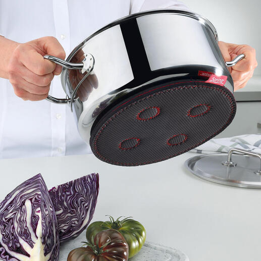 Hand hält einen magnetischen Untersetzer unter einen Kochtopf.
