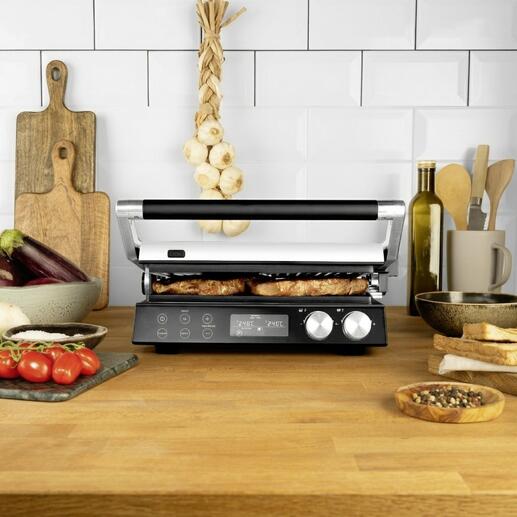 4-in-1 Multigrill auf einem Tisch mit gegrilltem Essen und frischen Zutaten.