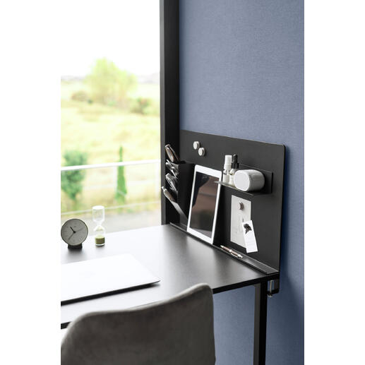 Schwarze magnetische Pinnwand mit Büroaccessoires auf einem Schreibtisch.