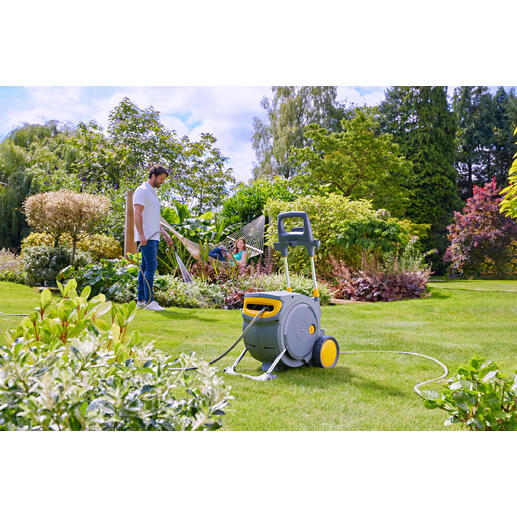 Mann gießt Wasser mit einem Schlauch aus einem geschlossenen Schlauchwagen