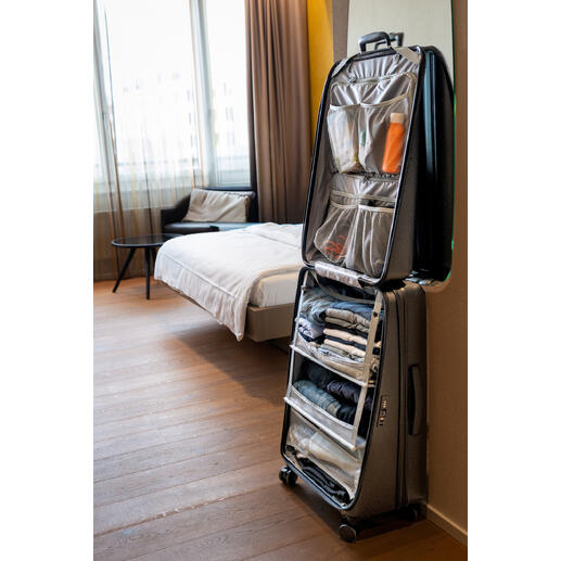 Schrankkoffer in einem Hotelzimmer, offen mit Kleidung und Zubehör.