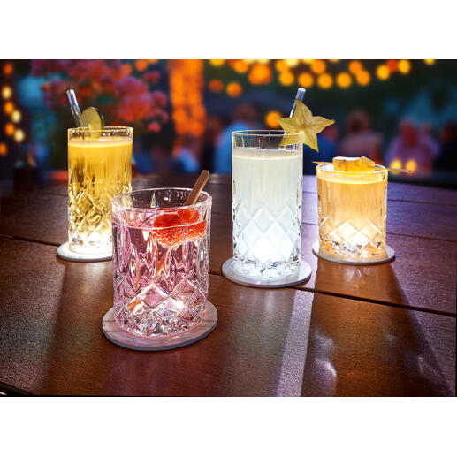 Vier beleuchtete Gläser auf einem Tisch mit LED-Untersetzer, ideal für eine festliche Atmosphäre.