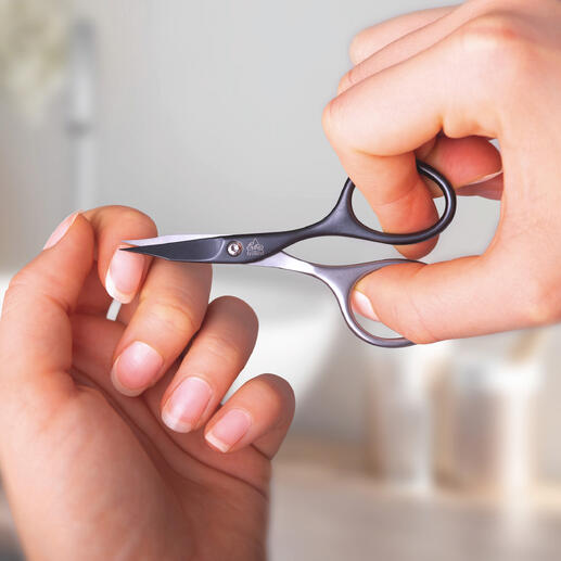 Person mit selbstschärfenden Maniküre-Scheren schneidet ihren Fingernagel.