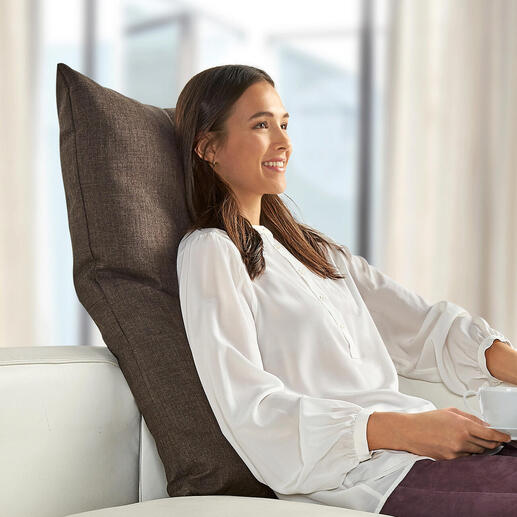 Frau mit braunem Rückenkissen auf einer weißen Couch.
