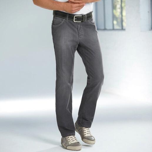 Mann in grauen Denim-Jeans und T-Shirt steht vor einem Fenster.